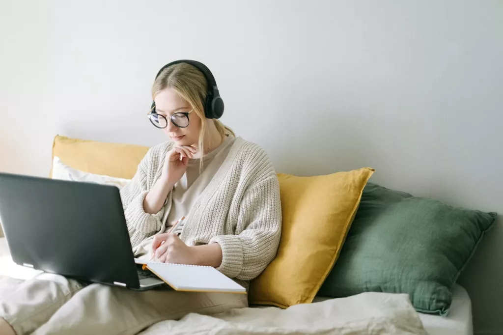 Jente sitter i sofa med PC på fanget