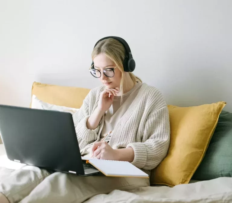 Jente sitter i sofa med PC på fanget