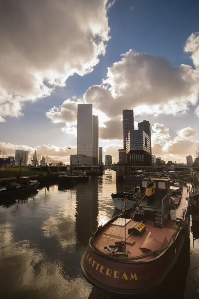 Havn i Rotterdam med båt og kontorblokker i bakgrunnen