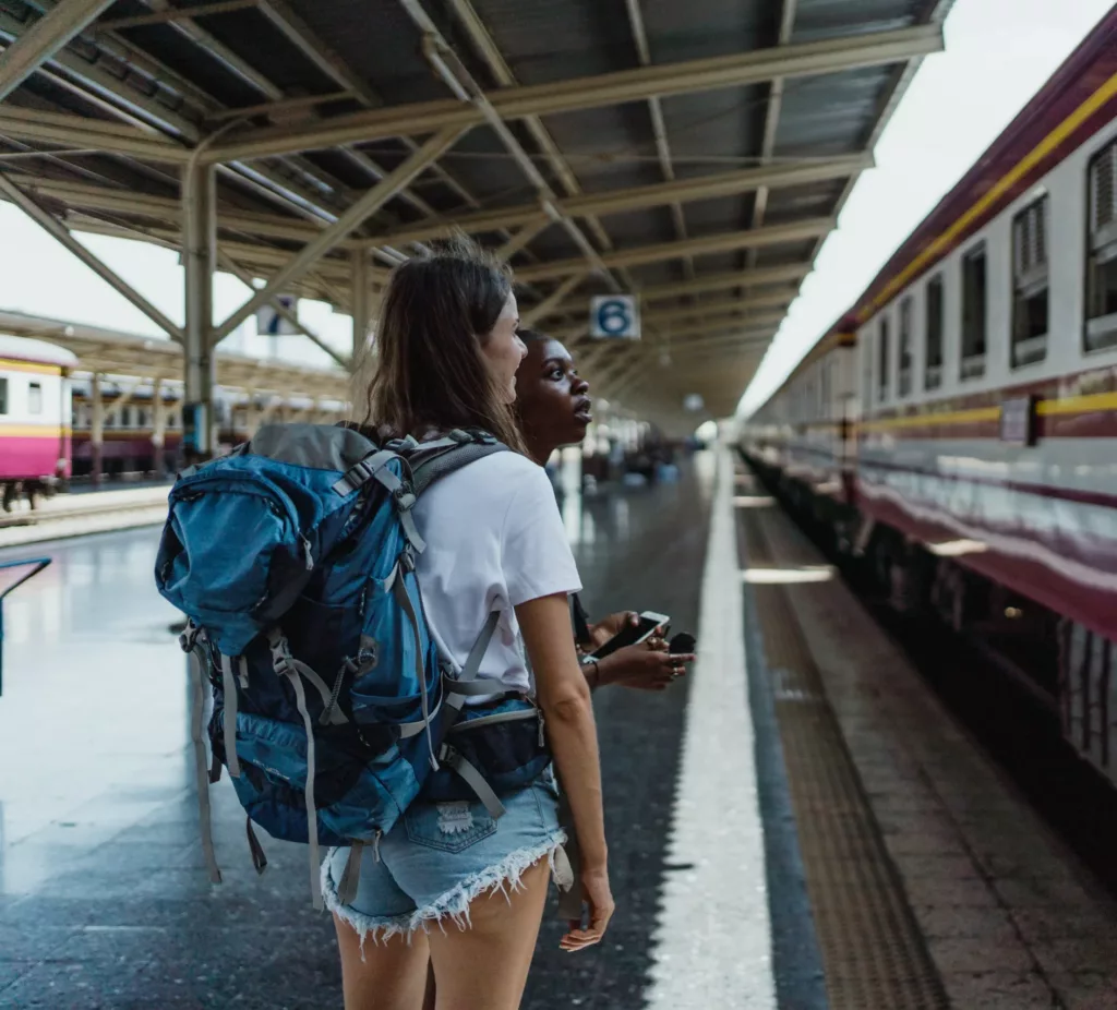 To unge kvinner står ved et tog på en togstasjon