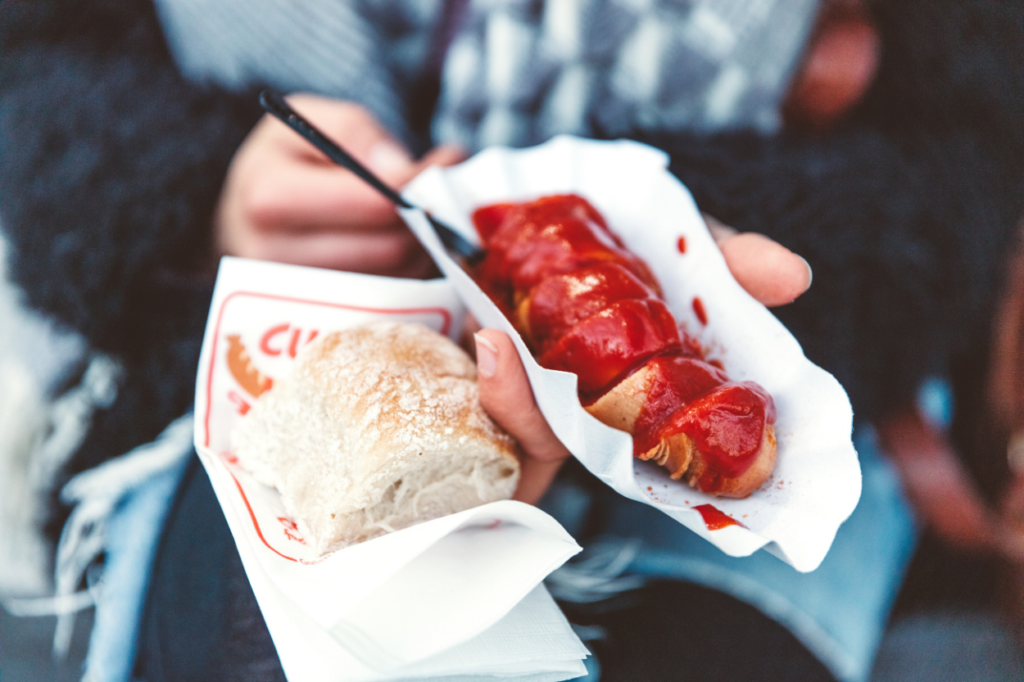 Hender holder pølse med saus og brød