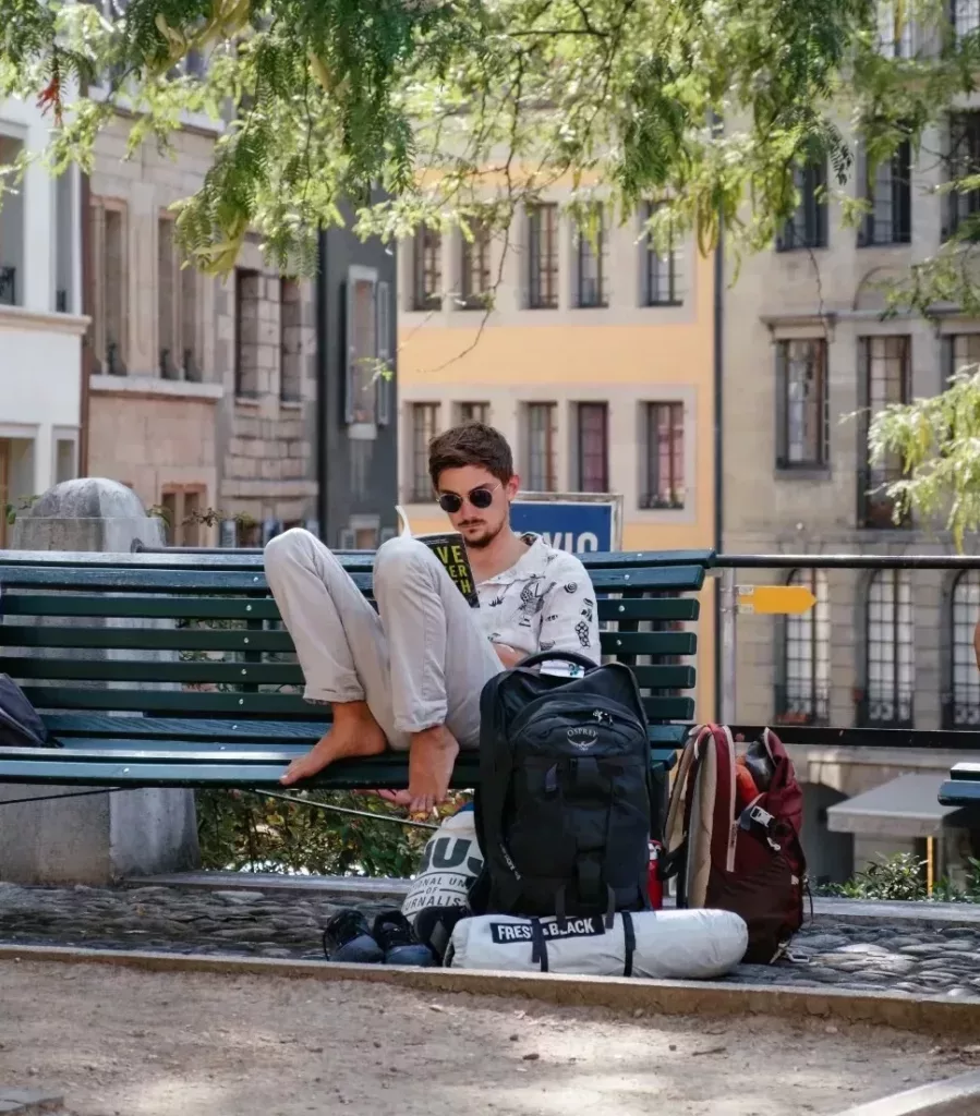 Ung mann med solbriller leser på en benk