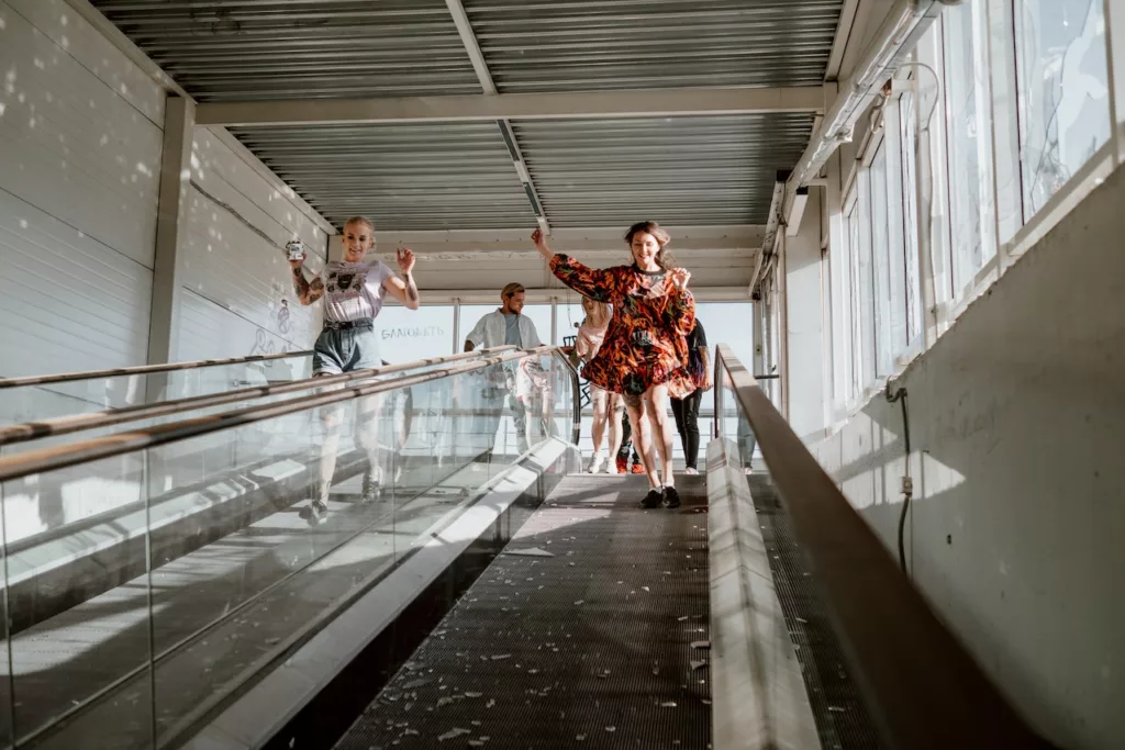 Glade, unge mennesker løper nedover rulletrapper
