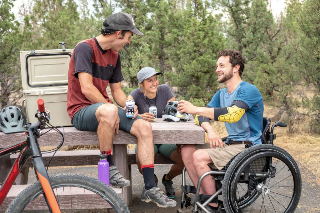 Ung mann i rullestol sitter ved et bord med to andre menn