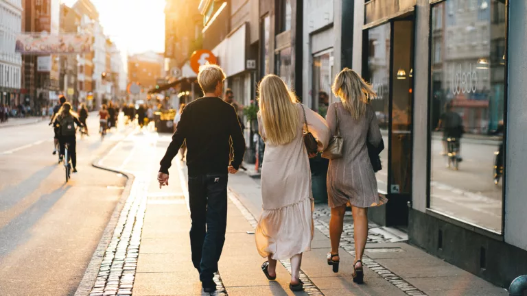 Tre personer går oppover gaten i sentrum av skandinavisk by