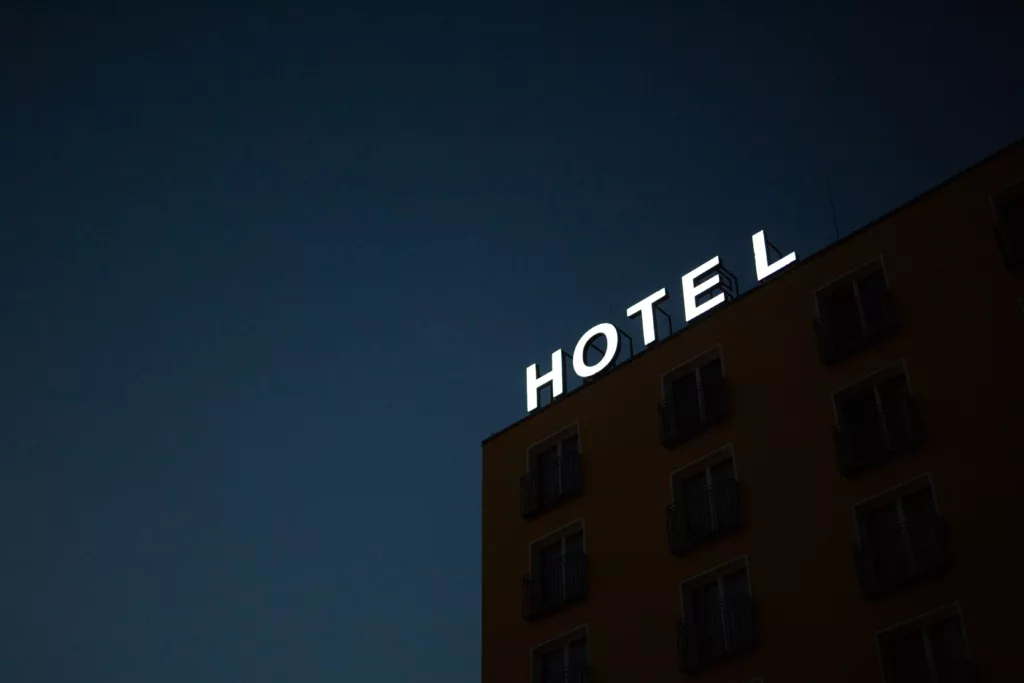 Hjørne av et bygg med lysende skilt som sier hotell