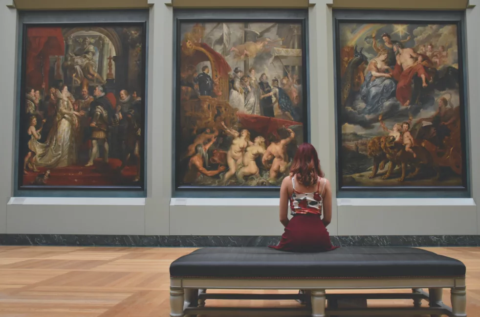 Dame som sitter og ser på maleri i et museum