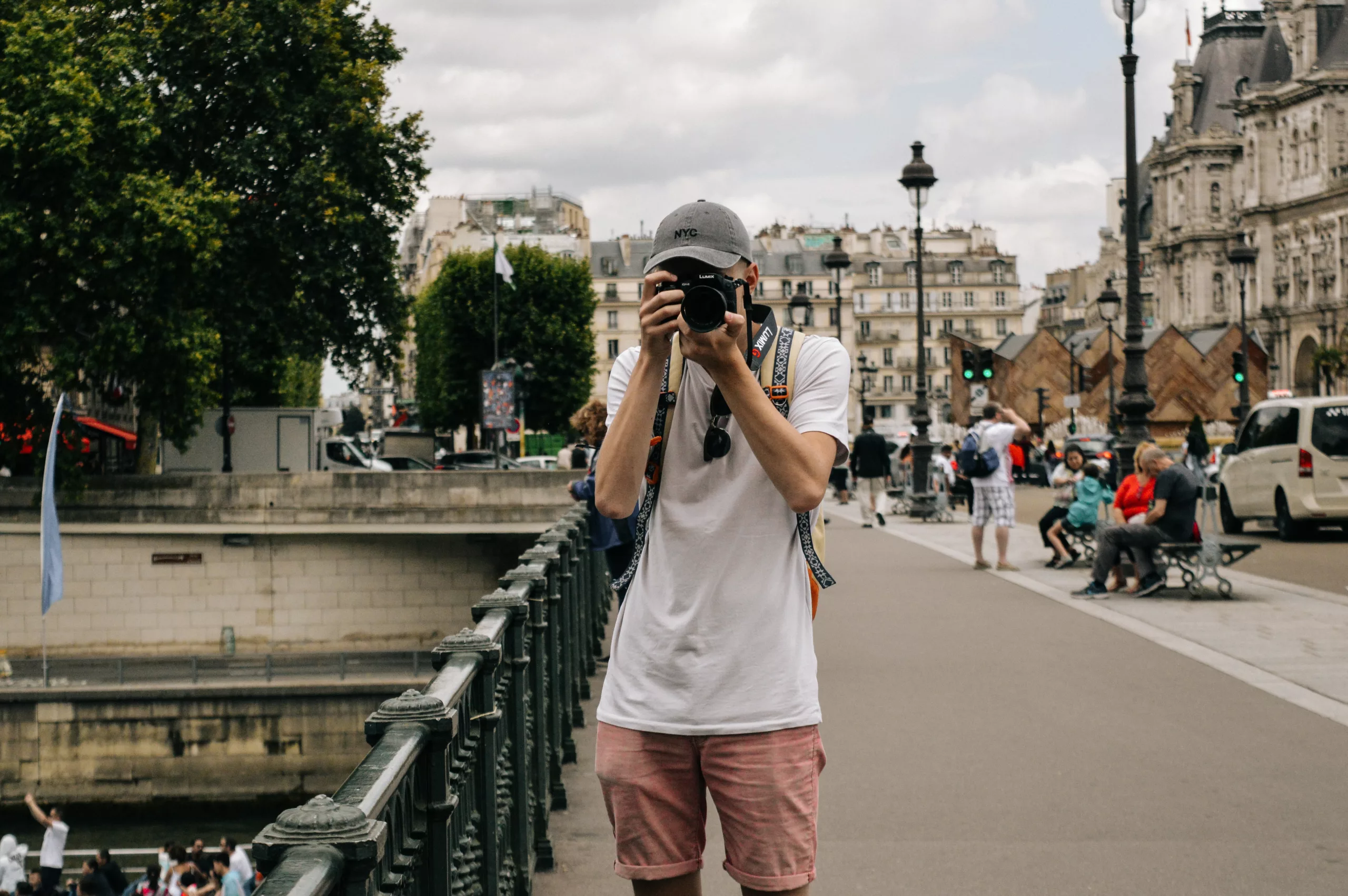 Ung mann med kamera rettet mot fotografen