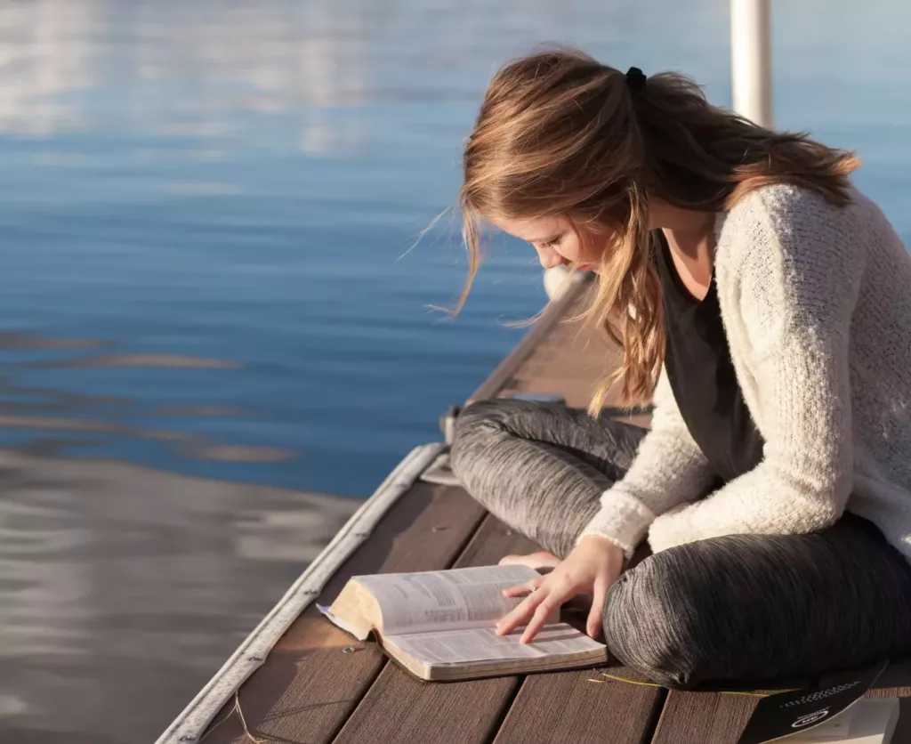 Kvinne sitter på en brygge og leser