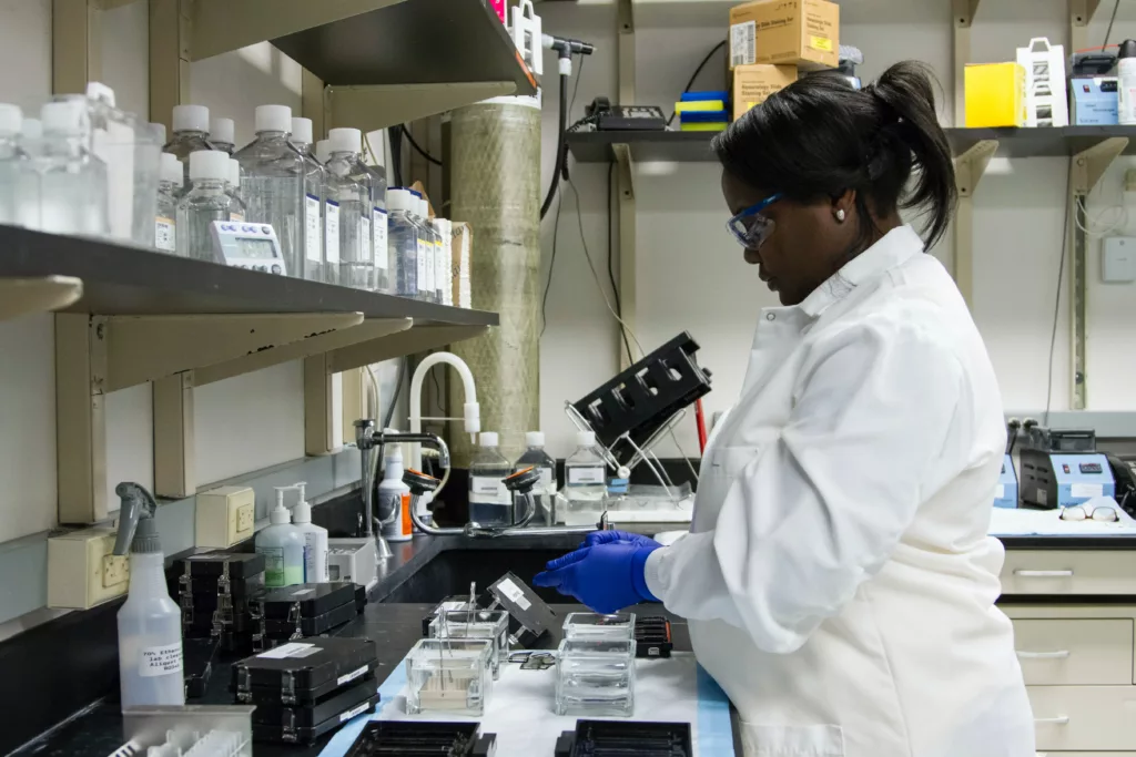 Ung kvinne med hvit frakk jobber i et laboratorium