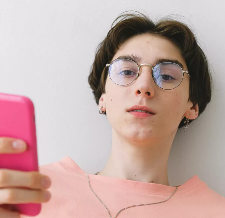 Ung person med rosa genser holder en rosa mobil