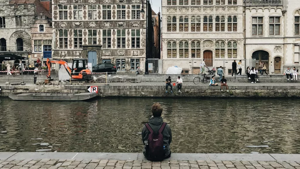 En ung mann sitter ved en kanal i Ghent i Belgia