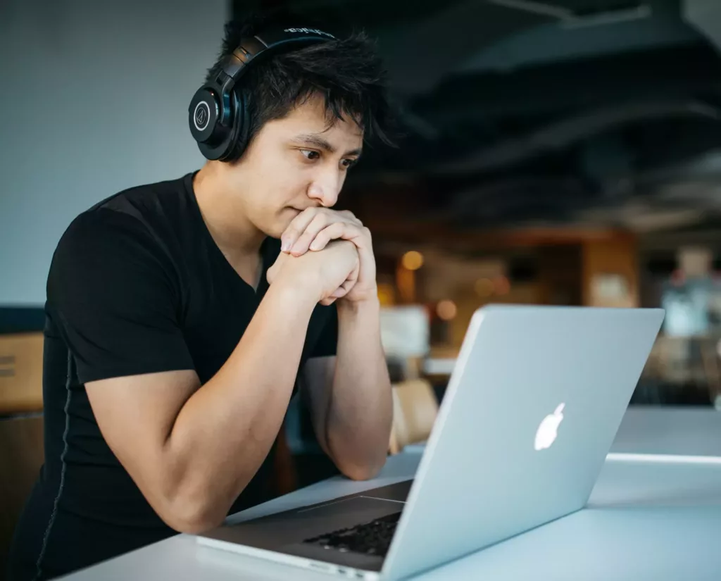 Ung mann med headset jobber på en laptop