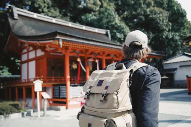 Mann med caps og lys sekk går ved et asiatisk tempel
