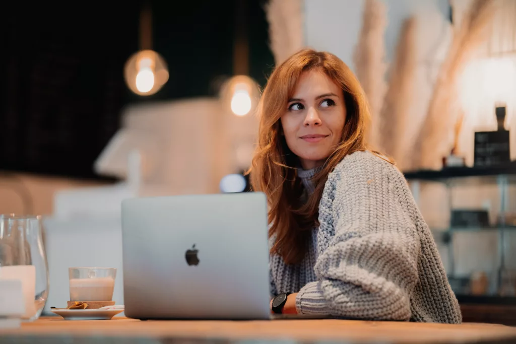 Kvinne med rødt hår sitter ved en pc