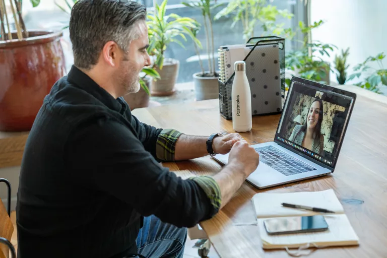 Mann sitter ved et bord og har videomøte på PC