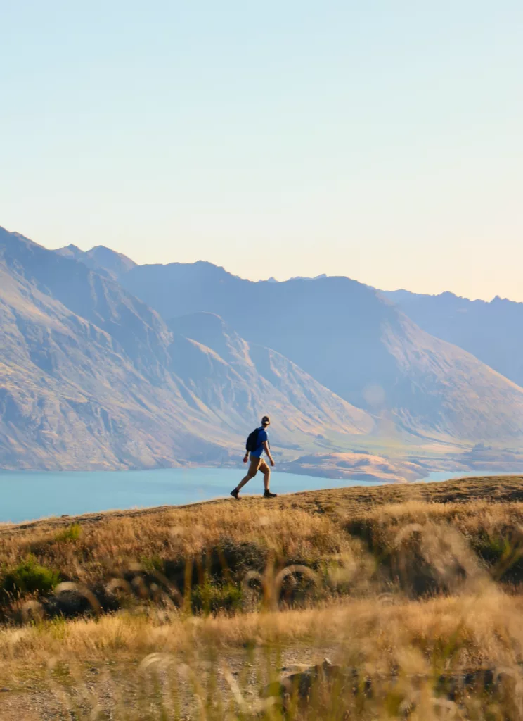 En mann med ryggsekk går tur på fjellene i New Zealand