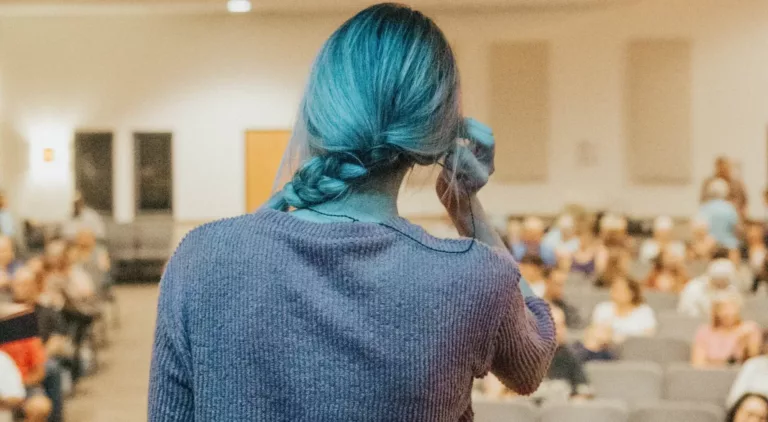 Kvinne med flettet hår sett bakfra foran et publikum