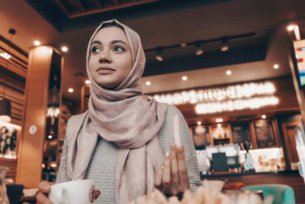 Kvinne med lys hijab på kafé