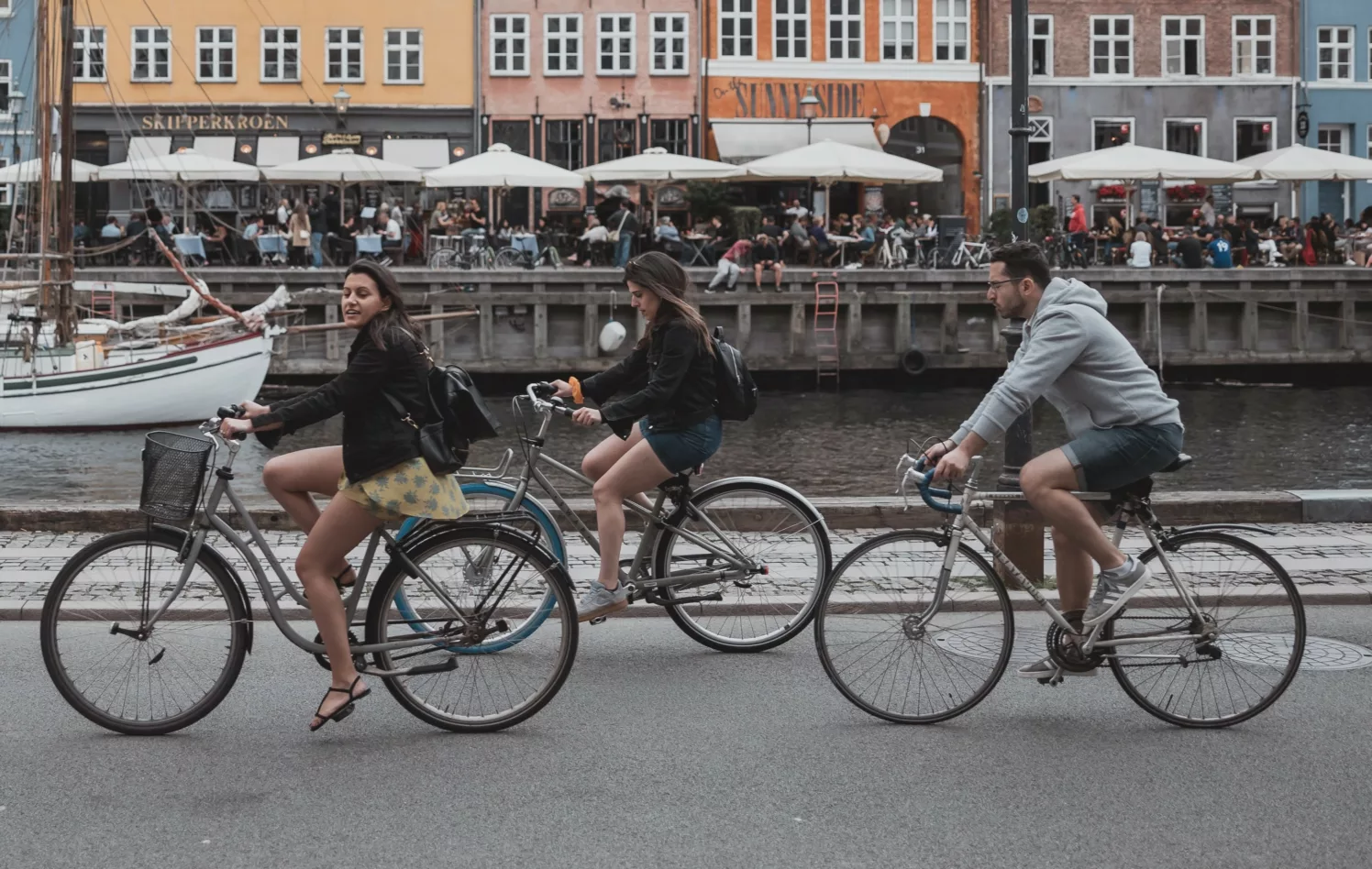 Tre personer sykler langs en brygge