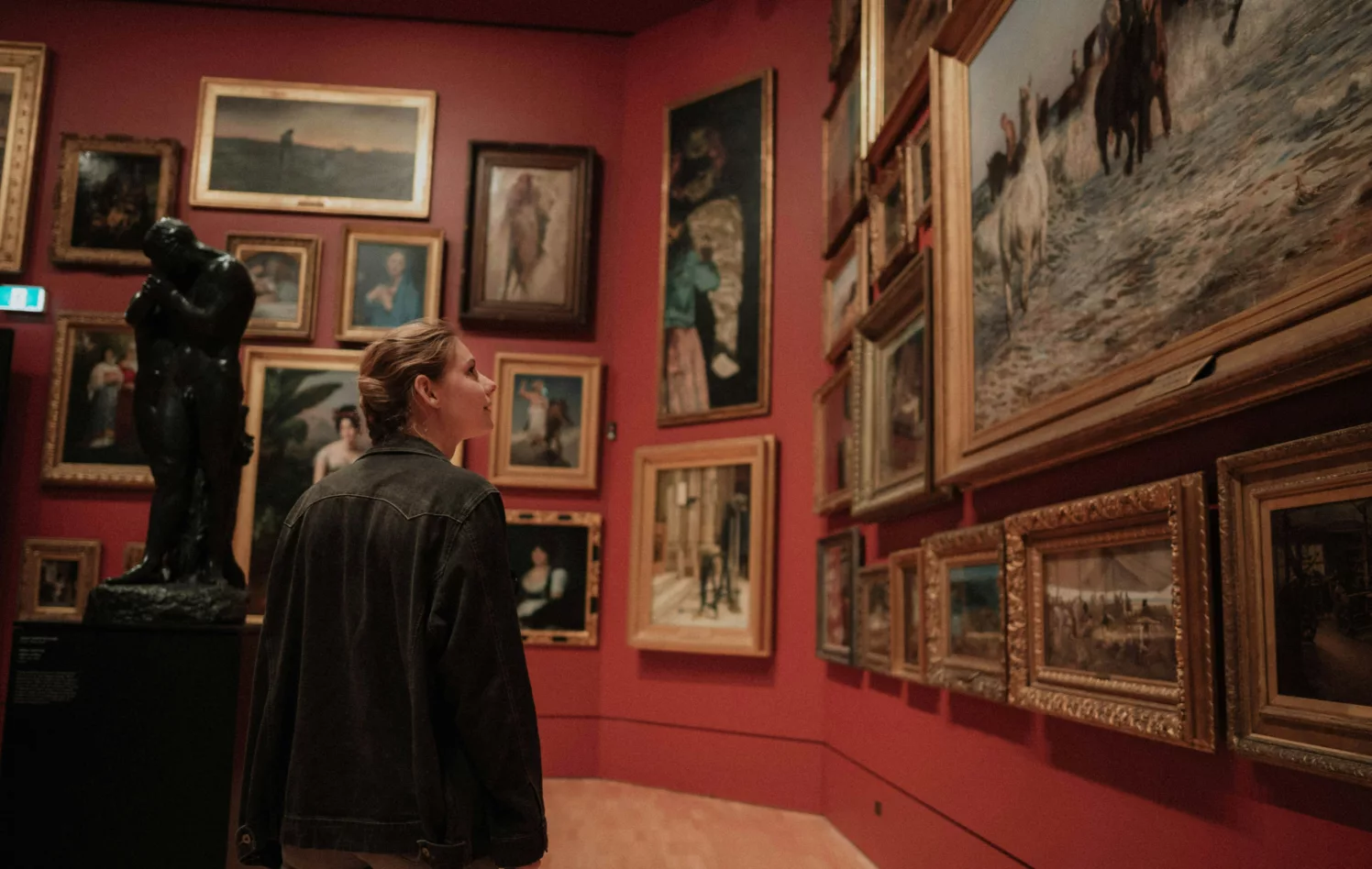Kvinne ser på kunst i et rødt rom