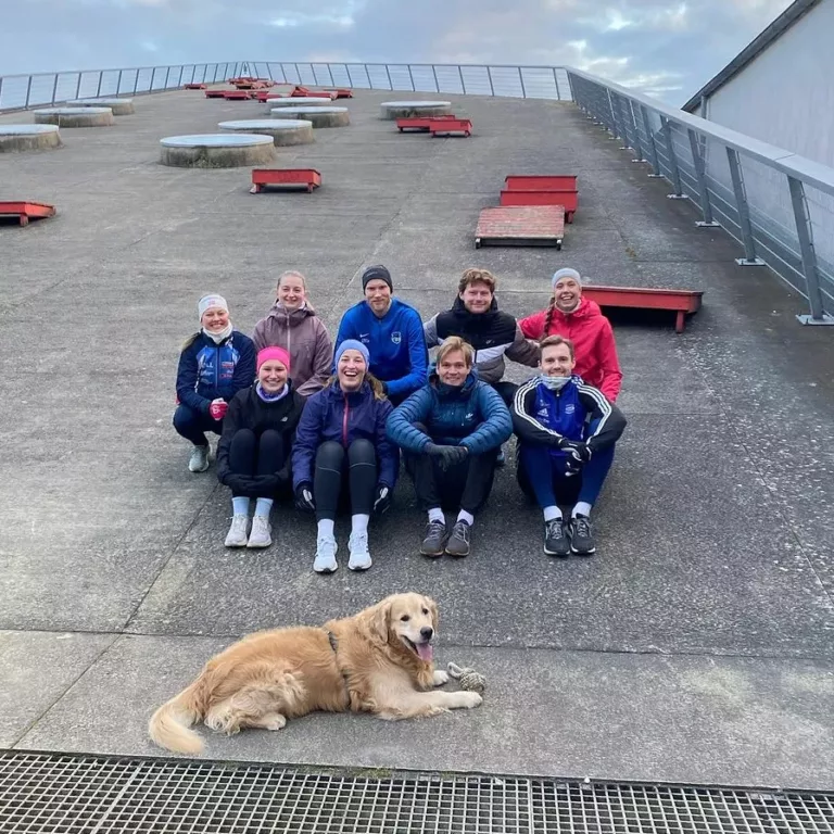 En gruppe med personer i treningstøy med en golden retriever